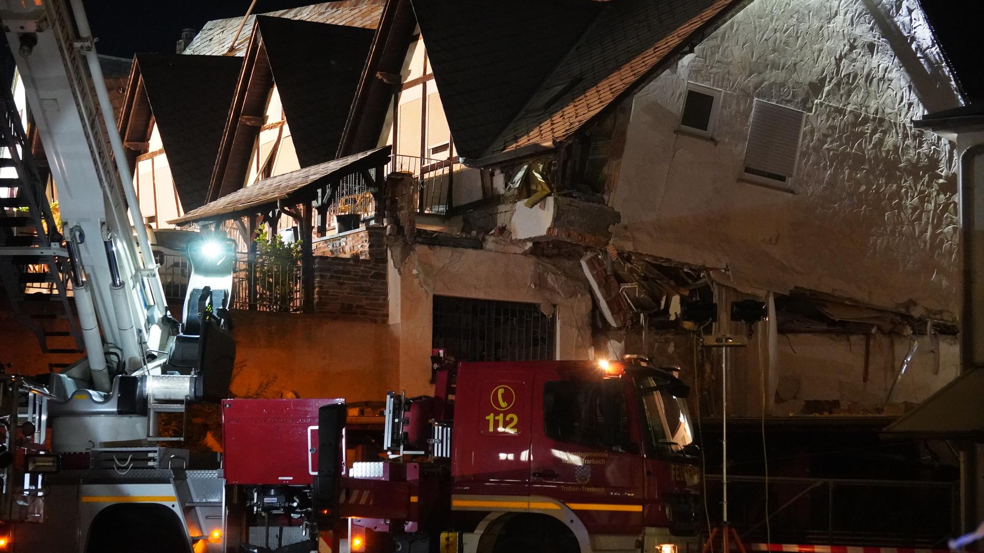 Ein Fahrzeug der Feuerwehr steht bei Nacht vor einem eingestürzten Hotel.