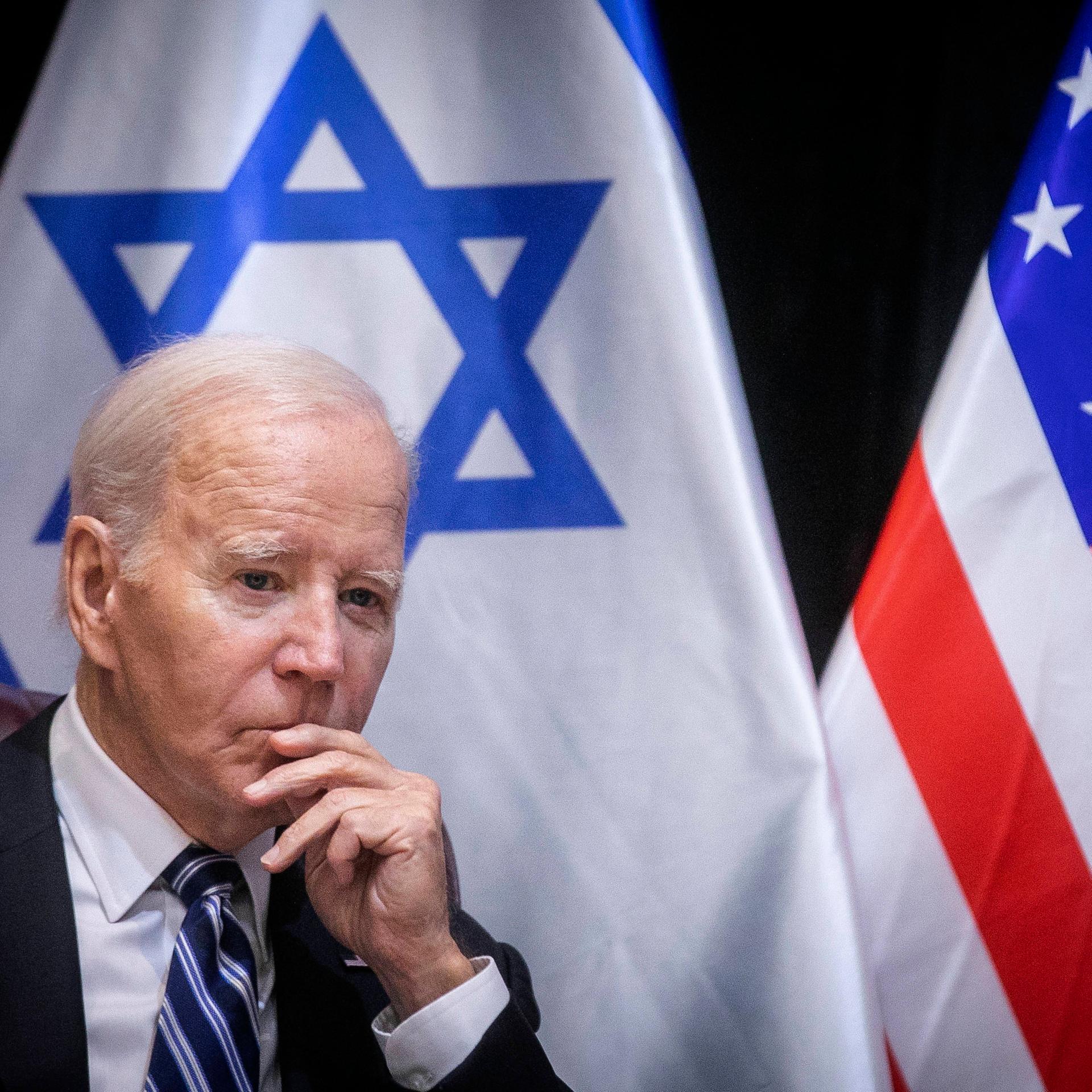 US-Präsident Joe Biden sitzt vor einer israelischen und einer US-amerikanischen Flagge.