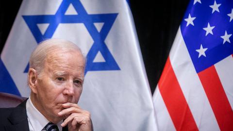 US-Präsident Joe Biden sitzt vor einer israelischen und einer US-amerikanischen Flagge.