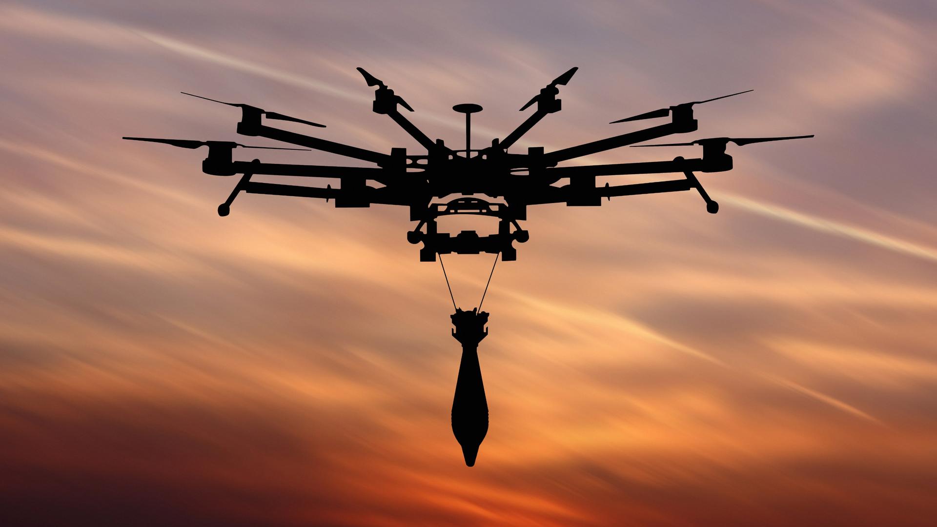 Unter der Drohne hängt eine Bombe an zwei Drähten. Im Hintergrund ist ein Sonnenuntergangshimmel zu sehen.