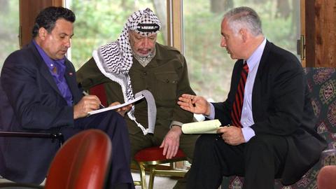 Der israelische Ministerpräsident Benjamin Netanjahu (l) trifft am 22.10.1998 in Wye River mit Palästinenser-Präsident Jassir Arafat (M) zusammen. Links Protokollant Nabil Abu Rudineh. Bei den Nahost-Verhandlungen in den USA hatten sich Israel und die Palästinenser auf ein Abkommen geeinigt. Damit ist der Weg für einen israelischen Rückzug aus weiteren 13 Prozent des besetzten Westjordanlandes frei. AuÃerdem einigten sich die Unterhändler auf eine Zusammenarbeit gegen Extremisten, eine Tilgung anti-israelischer Passagen der Palästina-Charta und die Entlassung eines Teils der palästinensischen Gefangenen durch Israel.