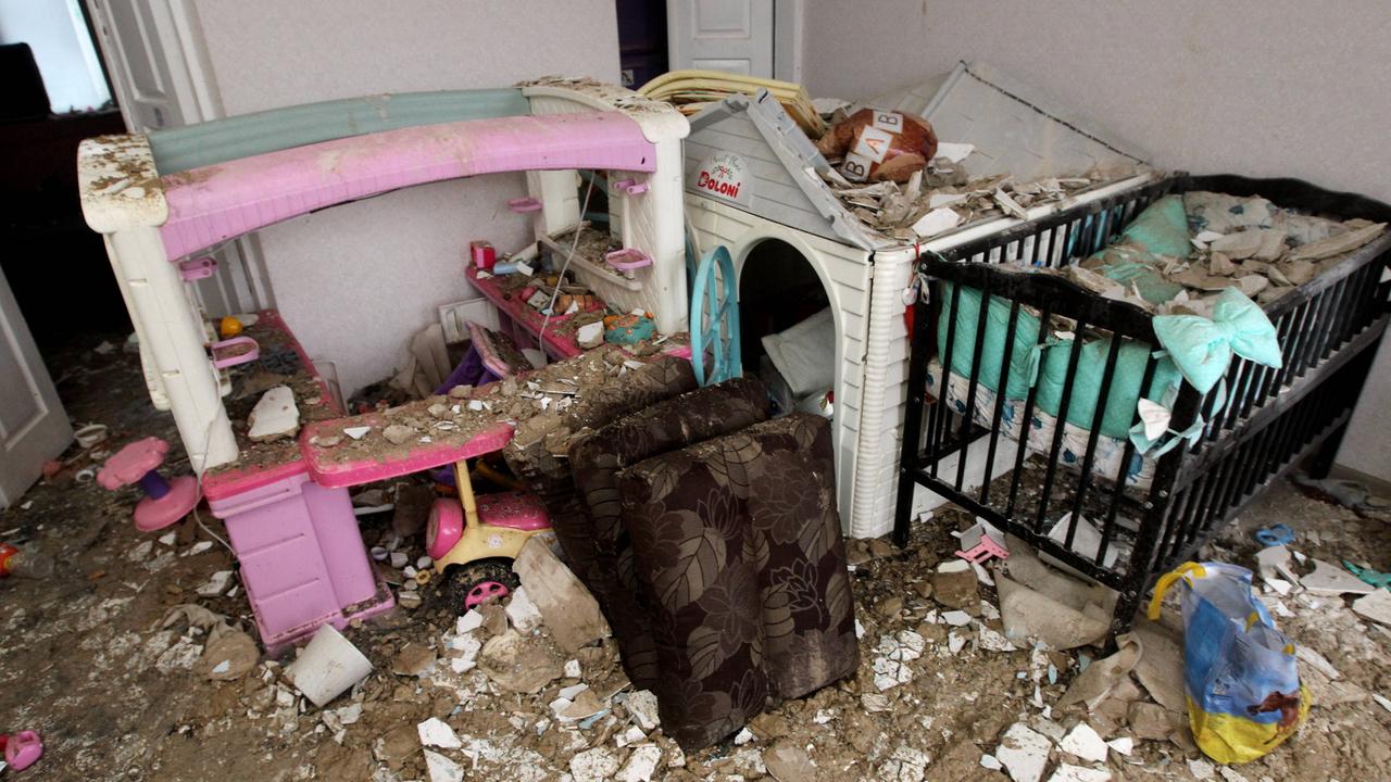 Man sieht ein Kinderzimmer mit einem Gitterbett und einem Puppenhaus, drumherum viel Schutt. Aufgenommen wurde das Foto am 12. Februar 2026 in Dnipro (Ukraine), nachdem das Wohngebäude von einer russischen Drohne getroffen wurde.