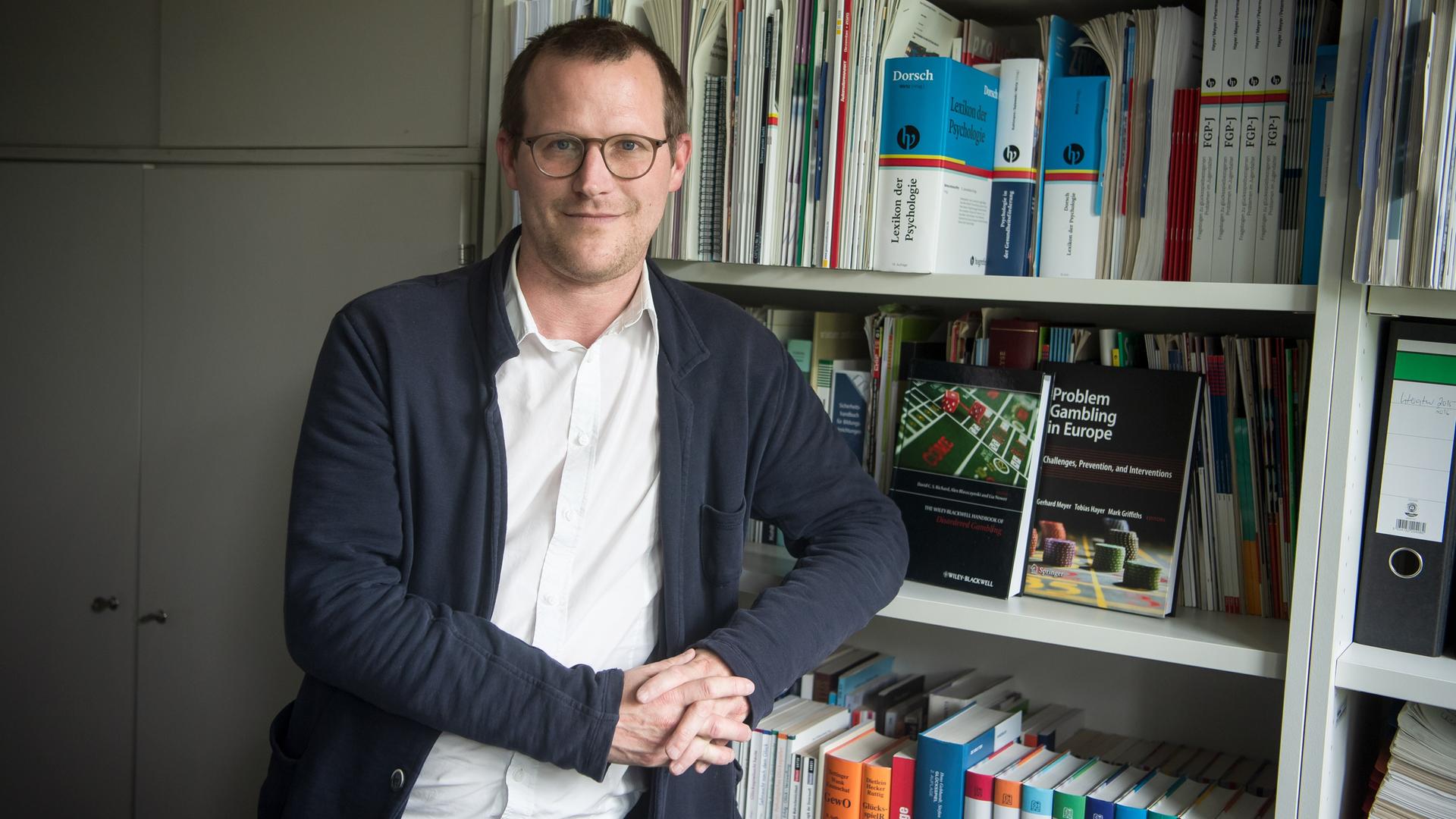 Tobias Hayer, Glücksspielforscher, steht in seinem Büro vor einem Bücherregal. Tobias Hayer, Glücksspielforscher, steht in seinem Büro vor einem Bücherregal.