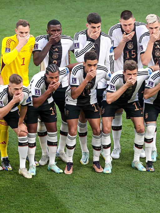 Die Spieler der deutschen Fußballnationalmannschaft stellen sich zum Foto auf und halten sich die Hand vor den Mund.