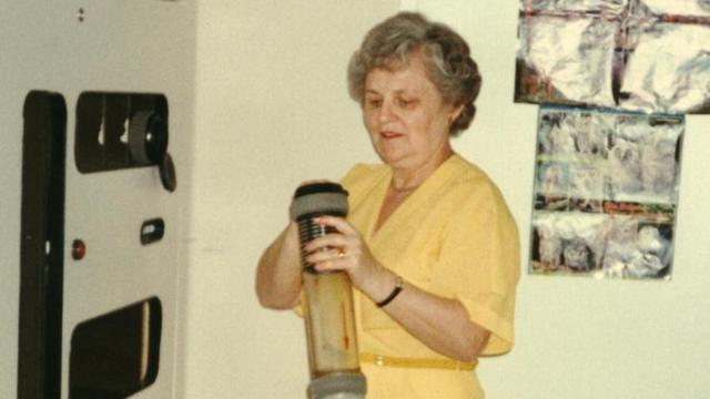Eine Frau in gelbem Kostüm bedient die Rohrpostanlage, 1989