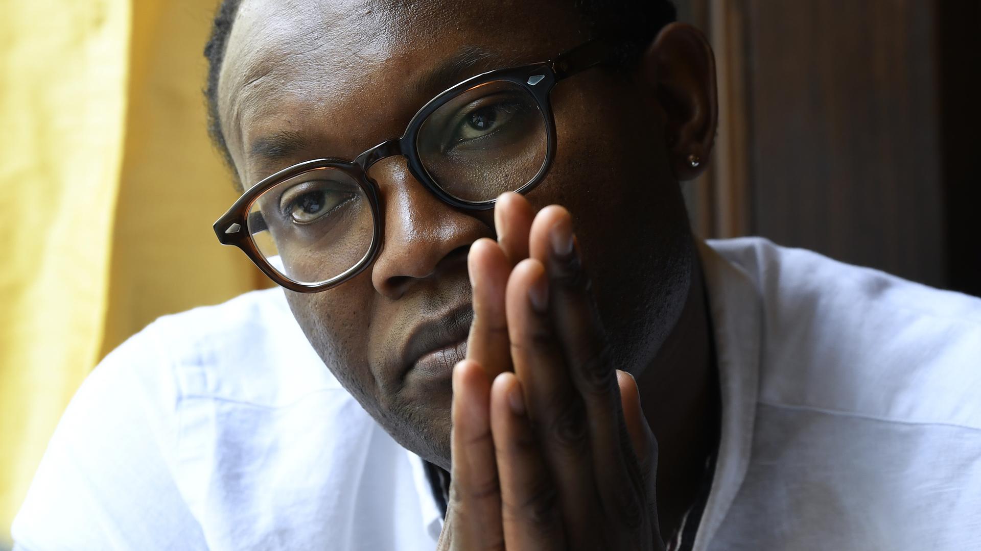 Der kongolesische Autor Fiston Mwanza Mujila während eines Interviews. Er legt die Handflächen vor seinem Gesicht aneinander.