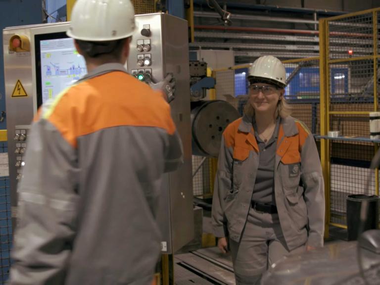 Stahlarbeiterin Lotti im Stahlwerk mit einem anderen Stahlarbeiter.