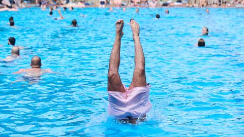 Am ersten Tag der Freibadsaison im Prinzenbad springt ein Schwimmer mit einem Kopfsprung ins Nass.