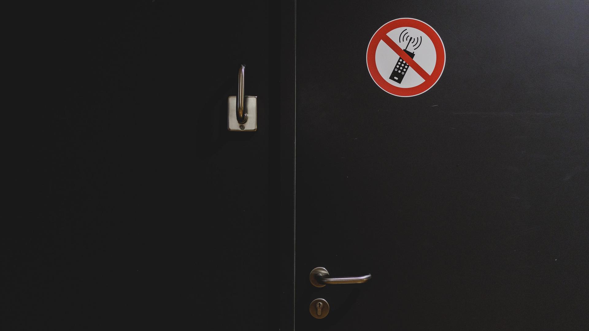Ein Hinweisschild zum Handyverbot klebt an einer Tür.