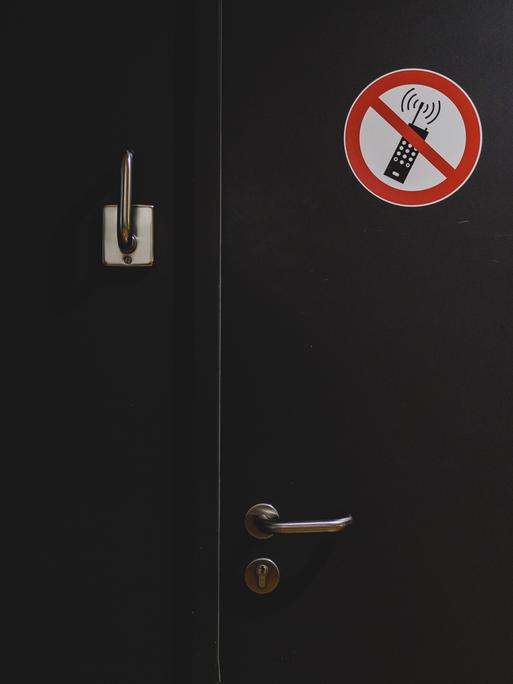 Ein Hinweisschild zum Handyverbot klebt an einer Tür.
