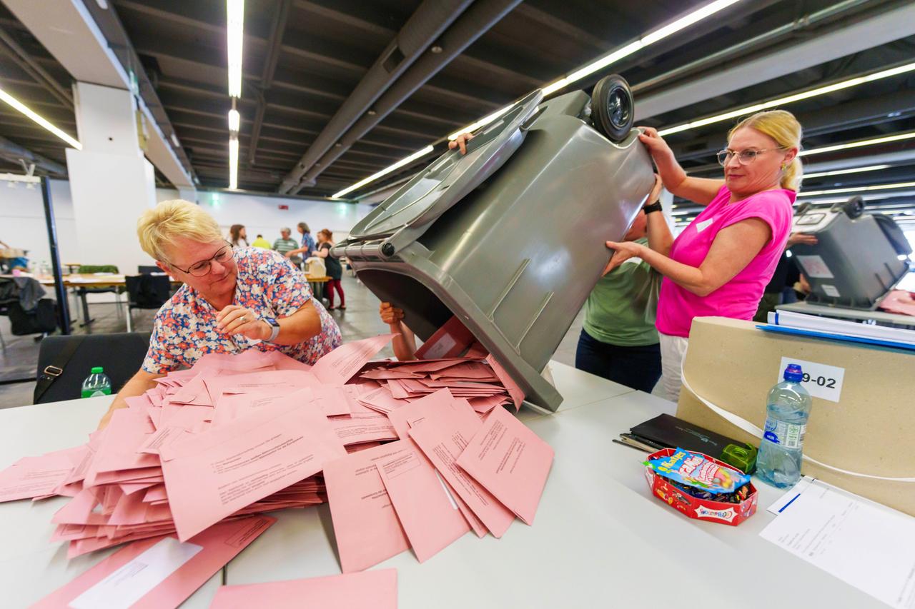 Wahl-Helferinnen öffnen Wahl-Urnen und breiten die Umschläge mit den Stimm-Zetteln aus. 