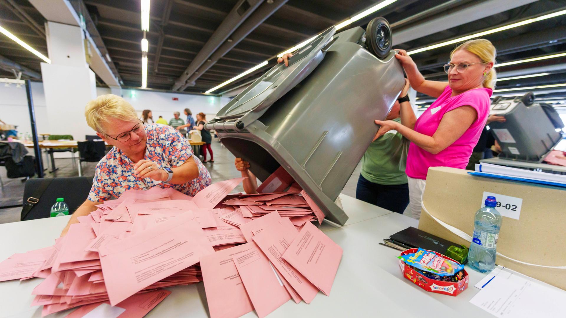 Wahlhelferinnen öffnen Briefwahlurnen und breiten die Umschläge mit den Stimmzetteln aus. 