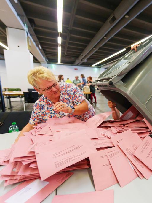 Wahlhelferinnen öffnen Briefwahlurnen und breiten die Umschläge mit den Stimmzetteln aus. 