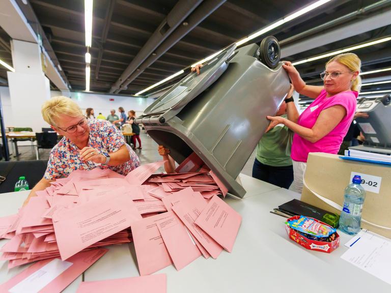 Wahlhelferinnen öffnen Briefwahlurnen und breiten die Umschläge mit den Stimmzetteln aus. 