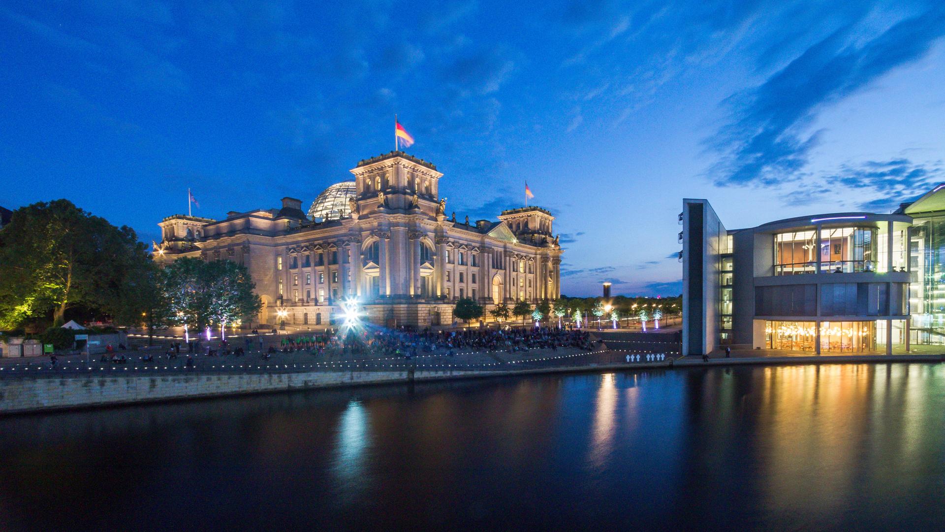 Panorama des Berliner Reichstags neben dem Deutschen Bundestag bei Nacht.