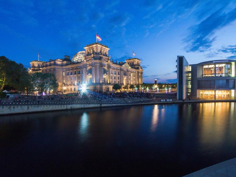 Panorama des Berliner Reichstags neben dem Deutschen Bundestag bei Nacht.