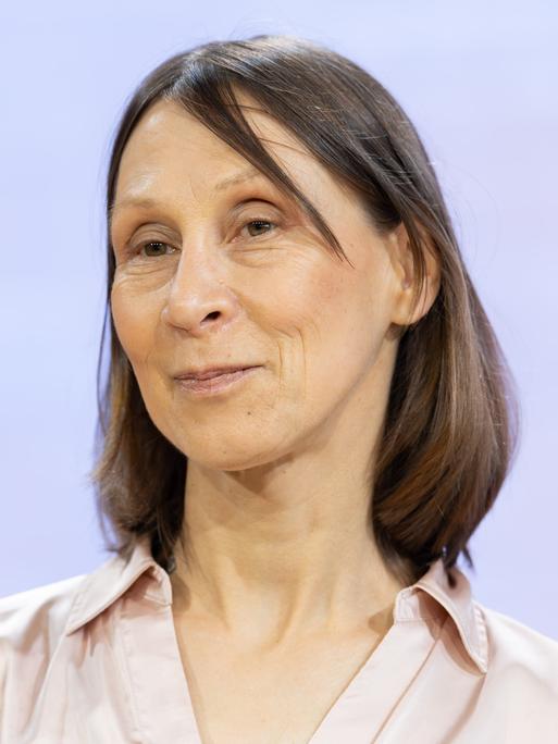 Die Schriftstellerin Martina Hefter im Porträt vor hellblauem Hintergrund 