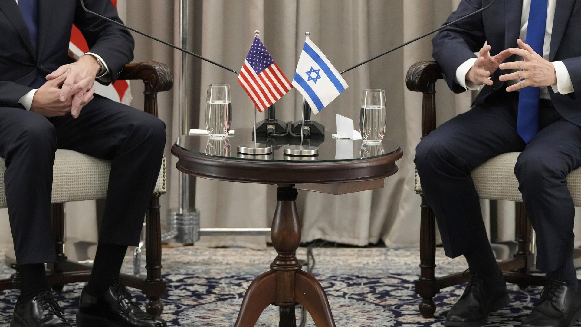 Die US-amerikanische und die israelische Fahne nebeneinander auf einem Tisch bei einem diplomatischen Treffen.