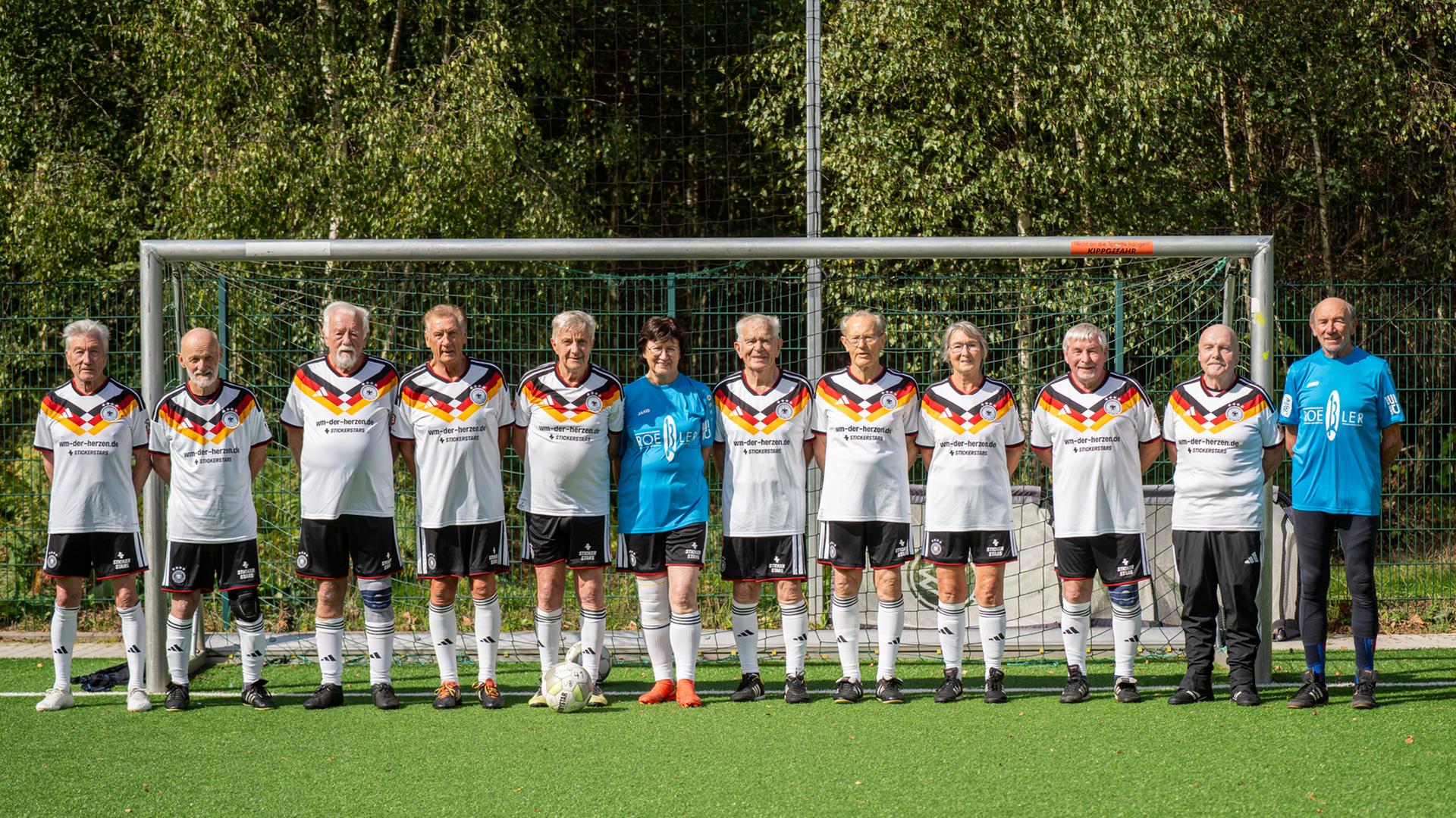 Die deutschen Ü80-Fußballer stehen aufgereiht auf dem Fußballplatz