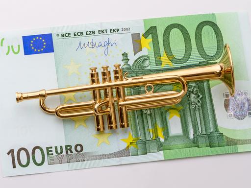 Eine kleine Modelltrompete liegt auf einem 100-Euro-Schein.