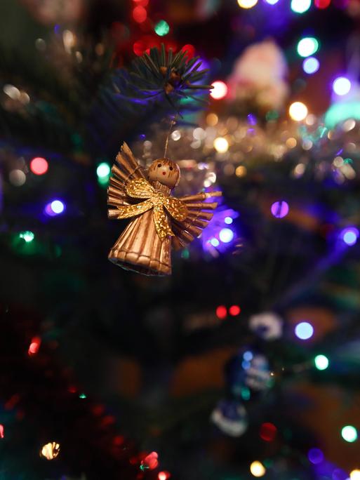 Ein goldener Engel und eine Eule in Nahaufnahme am Weihnachtsbaum hängend Ein goldener Engel und eine Eule in Nahaufnahme am Weihnachtsbaum hängend