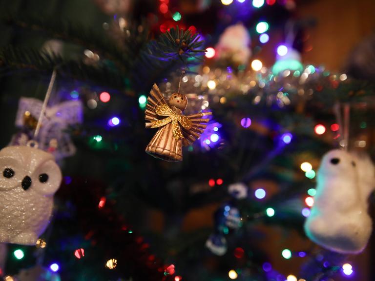 Ein goldener Engel und eine Eule in Nahaufnahme am Weihnachtsbaum hängend Ein goldener Engel und eine Eule in Nahaufnahme am Weihnachtsbaum hängend