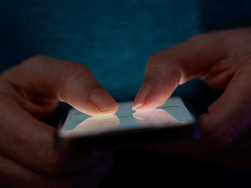 Frauenhände tippen auf einem Smartphone.