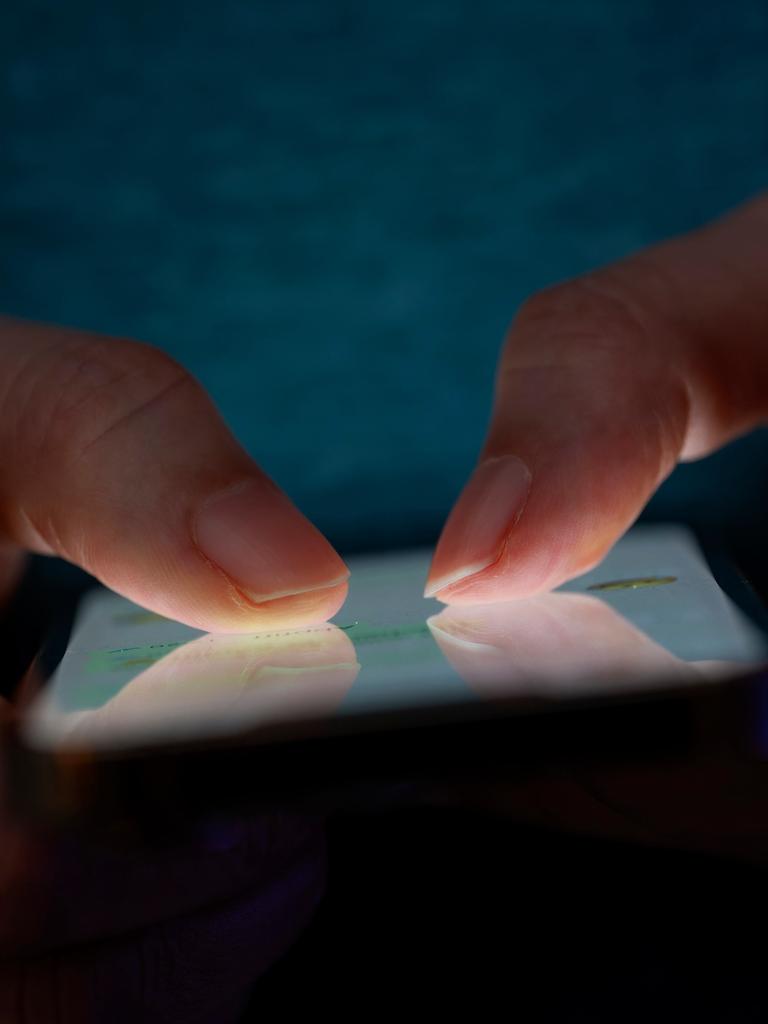 Frauenhände tippen auf einem Smartphone.