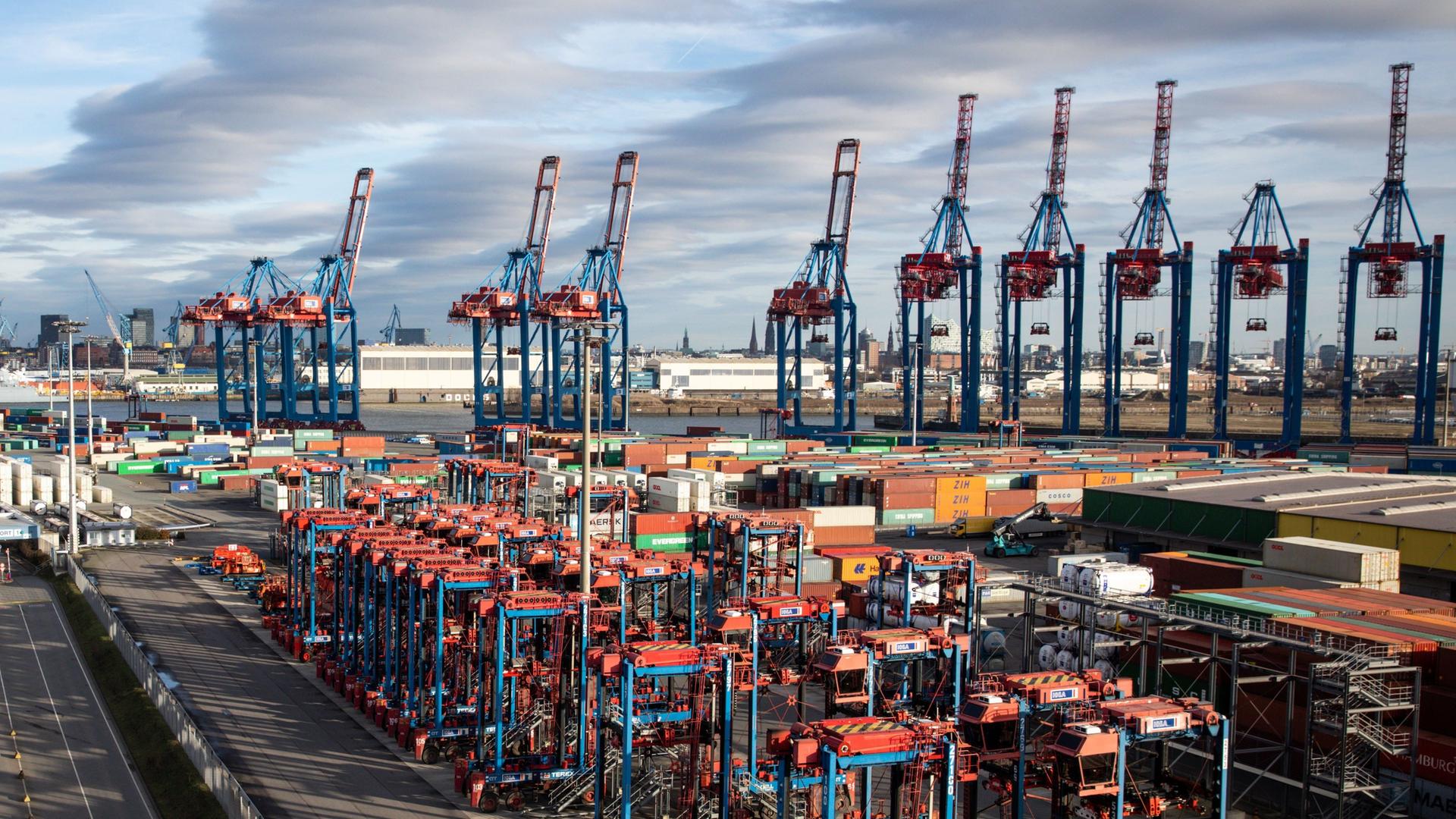 Auf einem großen Gelände stehen zahlreiche Container und Kräne. Auf einem großen Gelände stehen zahlreiche Container und Kräne.