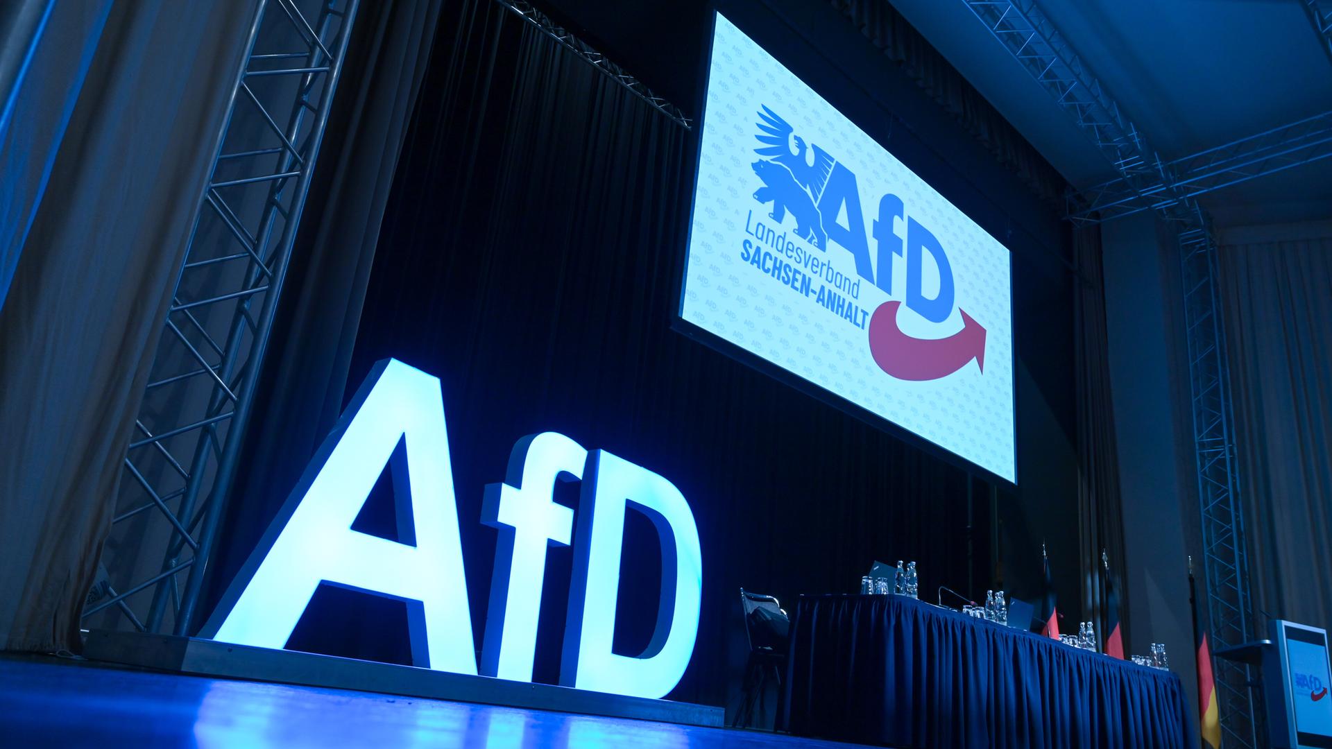 AfD-Schriftzug und das AfD-Logo auf der Bühne einem Versammlungssaal. AfD-Schriftzug und das AfD-Logo auf der Bühne einem Versammlungssaal.