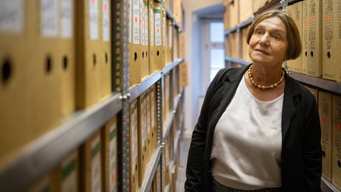Renate Ellmenreich steht zwischen Regalen mit Aktenordnern in der Stasiunterlagenbehörde in Erfurt