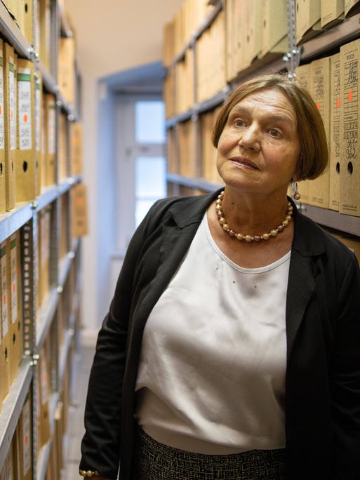 Renate Ellmenreich steht zwischen Regalen mit Aktenordnern in der Stasiunterlagenbehörde in Erfurt