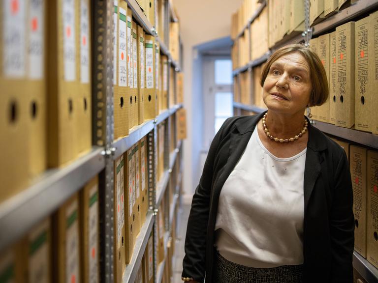 Renate Ellmenreich steht zwischen Regalen mit Aktenordnern in der Stasiunterlagenbehörde in Erfurt
