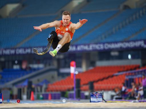 Markus Rehm trägt eine Unterschenkelprothese und springt in einem Stadion durch die Luft