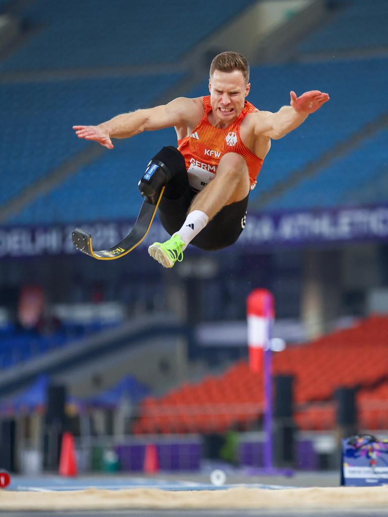 Markus Rehm trägt eine Unterschenkelprothese und springt in einem Stadion durch die Luft