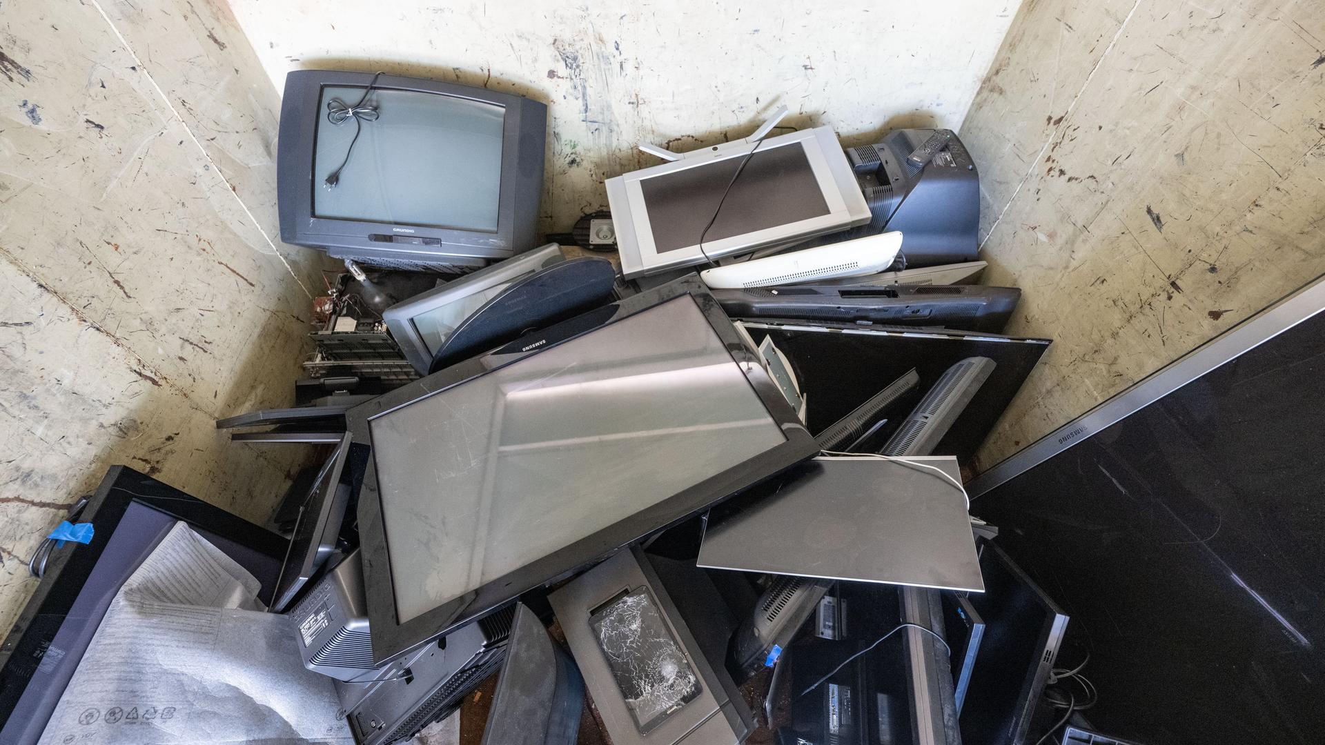 Alte und defekte Elektrogeräte liegen in einem Sammelcontainer auf einem Wertstoffhof. 