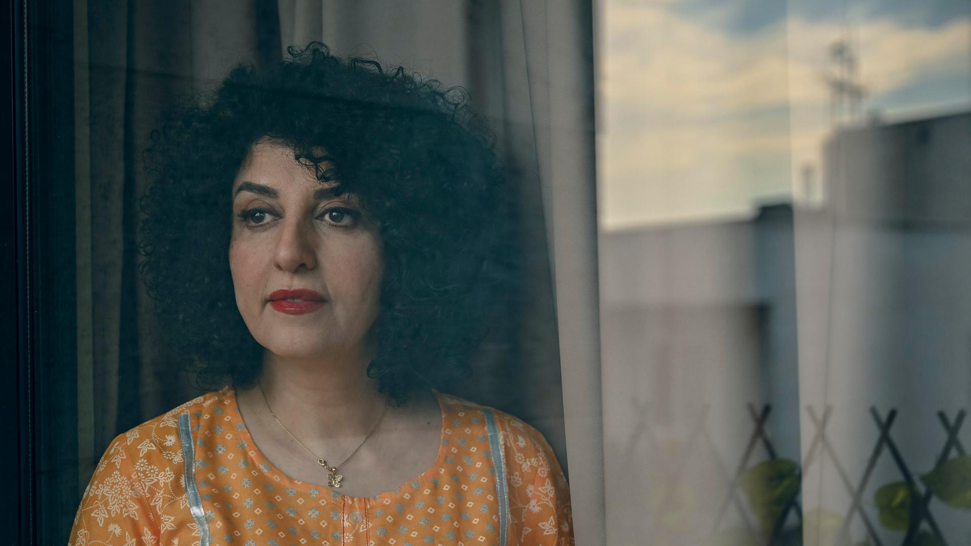 Narges Mohammadi steht mit gelber Bluse vor einem Fenster. Narges Mohammadi steht mit gelber Bluse vor einem Fenster.