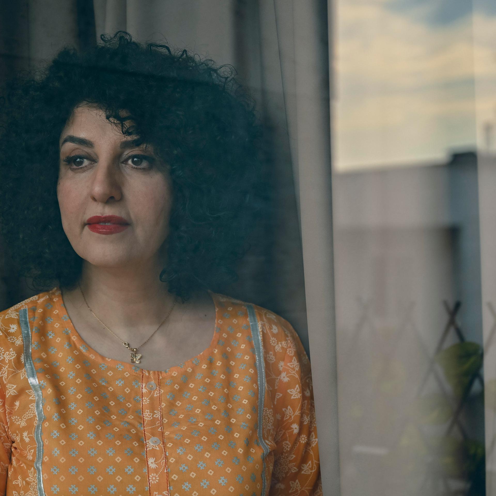 Die Friedensnobelpreisträgerin Narges Mohammadi steht mit gelber Bluse vor einem Fenster.