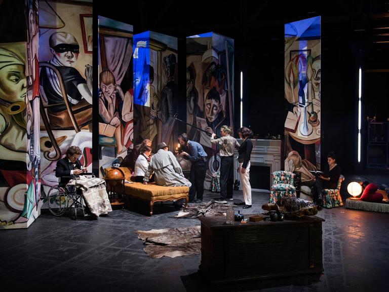 Eine Szene aus der Inszenierung "Der große Kunstraub" mit etlichen Bildteilen im Hintergrund mehrerer Akteure.