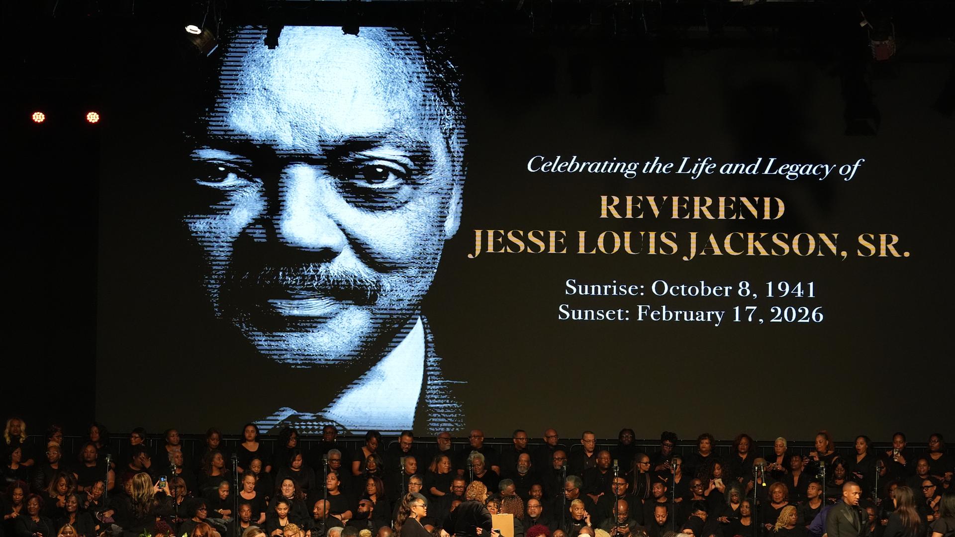 Menschen versammeln sich im Haus der Hoffnung. Im Hintergrund zu sehen ist ein Bild des verstorbenen US-Bürgerrechtlers Jesse Jackson.