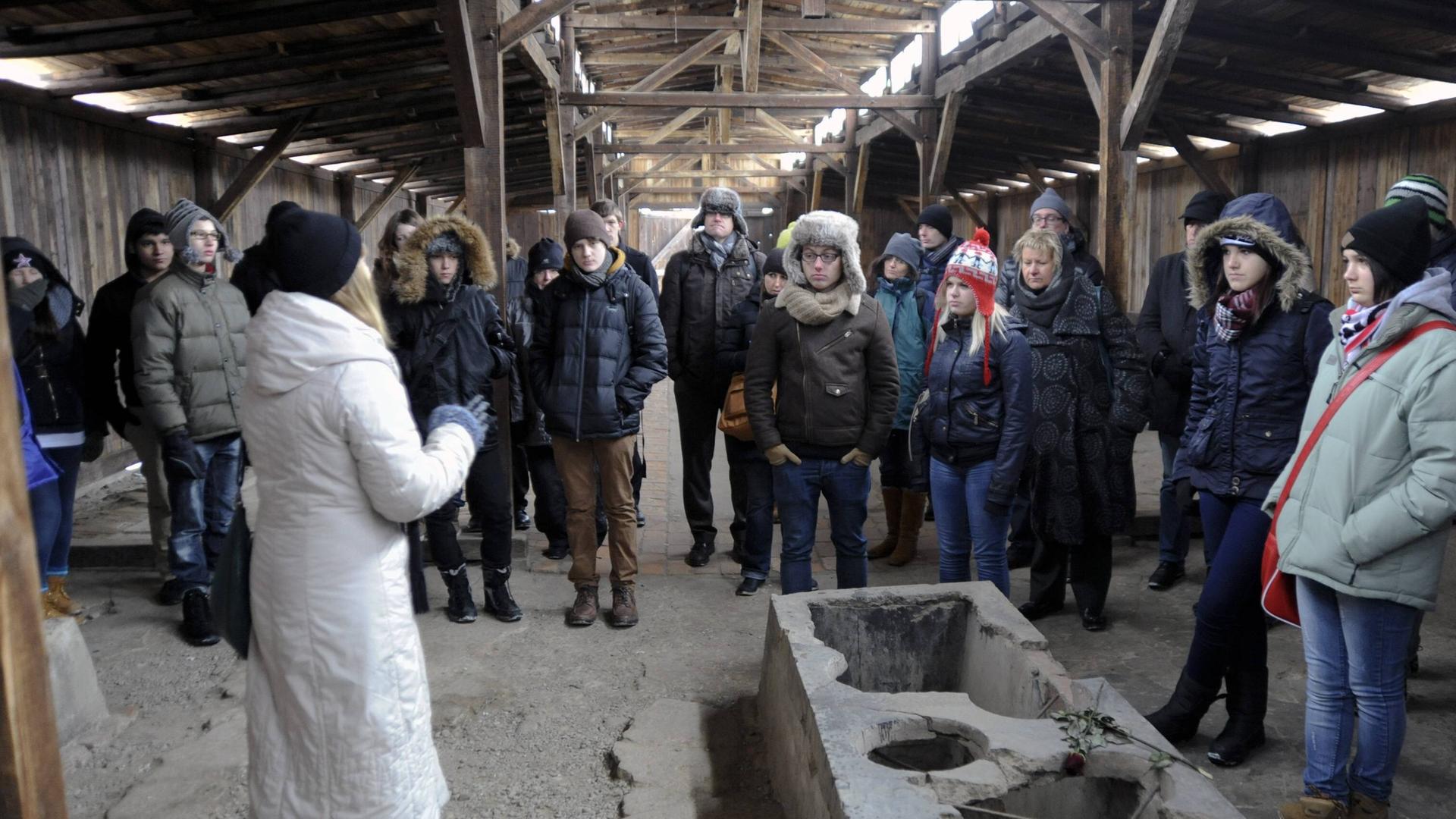 Eine Schulklasse aus NRW macht in der Gedenkstätte Auschwitz in Polen am 25.01.2013 eine Führung. Die Guide und die Schülerinnen und Schüler tragen Wintersachen und Mützen.