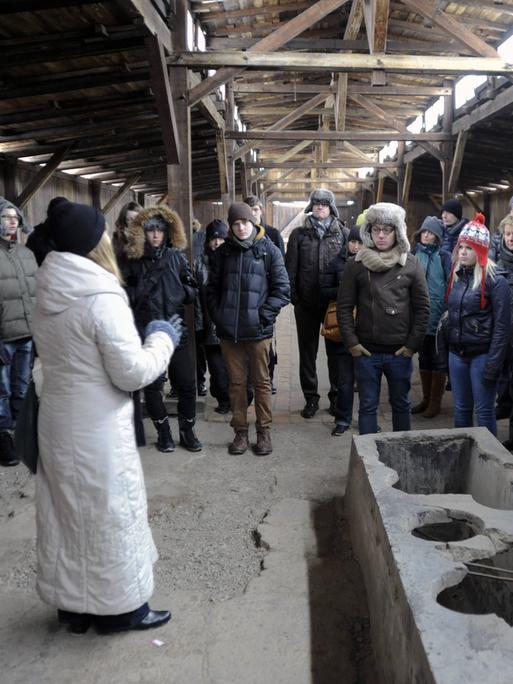 Eine Schulklasse aus NRW macht in der Gedenkstätte Auschwitz in Polen am 25.01.2013 eine Führung. Die Guide und die Schülerinnen und Schüler tragen Wintersachen und Mützen.