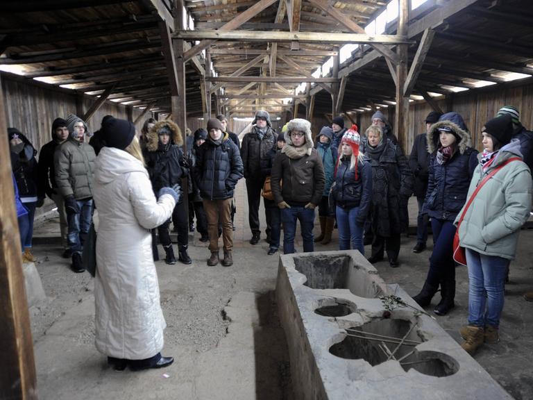 Eine Schulklasse aus NRW macht in der Gedenkstätte Auschwitz in Polen am 25.01.2013 eine Führung. Die Guide und die Schülerinnen und Schüler tragen Wintersachen und Mützen.