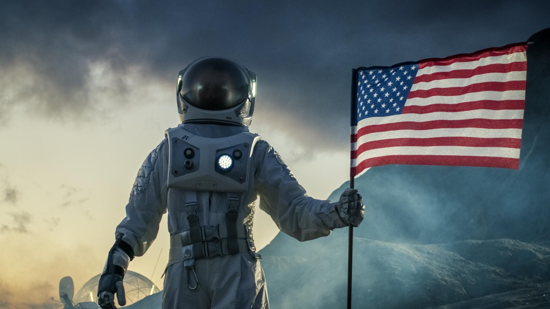 Ein Astronaut trägt einen Raumanzug und plaziert die US-amerikanische Flagge auf dem Mars.
