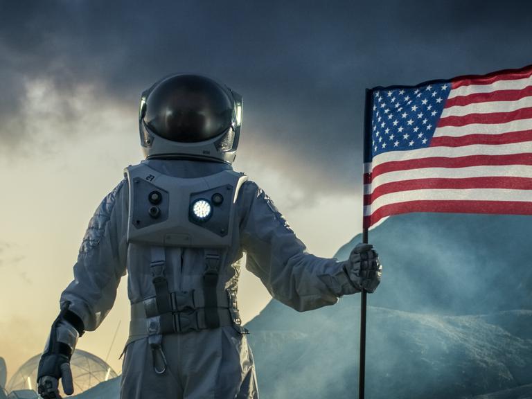 Ein Astronaut trägt einen Raumanzug und plaziert die US-amerikanische Flagge auf dem Mars.