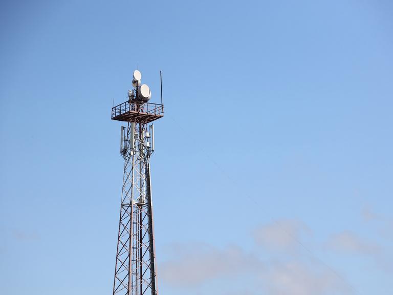 Telekommunikations-Antennen-Turm mit 4G und 5G vor einem blauen Himmel.