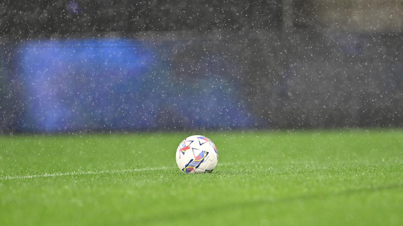 Ein Fußball auf dem leeren Spielfeld von Atalanta Bergamo in Italien. Es regnet in Strömen.