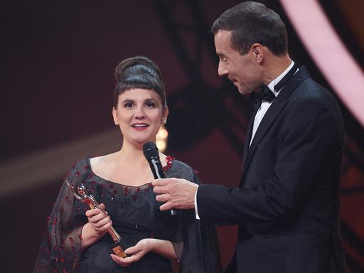 Miriam Peters in schwarzem Kleid nimmt während der Verleihung „Goldene Bild der Frau“ im Stage Theater an der Elbe auf der Bühne die Auszeichnung von Kai Pflaume entgegen.