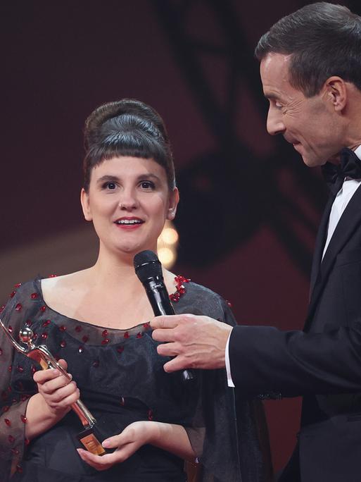 Miriam Peters in schwarzem Kleid nimmt während der Verleihung „Goldene Bild der Frau“ im Stage Theater an der Elbe auf der Bühne die Auszeichnung von Kai Pflaume entgegen.