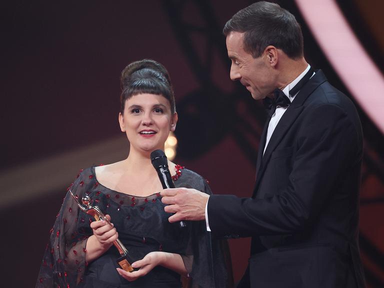 Miriam Peters in schwarzem Kleid nimmt während der Verleihung „Goldene Bild der Frau“ im Stage Theater an der Elbe auf der Bühne die Auszeichnung von Kai Pflaume entgegen.